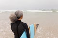 Senior female surfer walking towards the sea with surfboard on the beach Royalty Free Stock Photo