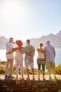 Rear View Of Senior Friends Visiting Tourist Landmark On Group Vacation Standing On Wall