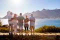 Rear View Of Senior Friends Visiting Tourist Landmark On Group Vacation Standing On Wall Royalty Free Stock Photo