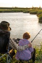 Rear view senior man and child boy engaged in fishing together, on countryside lake Royalty Free Stock Photo