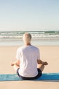 Rear view of senior man doing yoga at beach Royalty Free Stock Photo