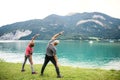 Rear view of senior pensioner couple by lake in nature, doing exercise.