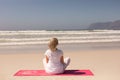 Rear view Senior woman meditating at beach on a sunny day Royalty Free Stock Photo