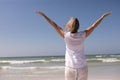 Rear view of senior woman standing with arms outstretched at beach Royalty Free Stock Photo
