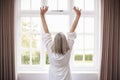 Rear View Of Senior Woman Stretching In Front Of Bedroom Window