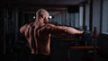 Rear view of a shirtless muscular man doing exercises with dumbbells in the gym. Royalty Free Stock Photo