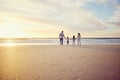 Rear view shot of a carefree family holding hands while walking into the sunset. Mixed race parents and their two kids Royalty Free Stock Photo