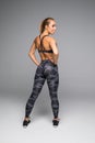 Rear view shot of a healthy young woman in sportswear. Full length image of muscular female model standing looking away at copyspa