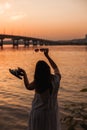 rear view of the silhouette of the back of a young woman holding sunglasses, slates in her outstretched hands and Royalty Free Stock Photo