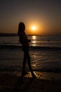 Rear view of a silhouette of the girl facing the sunset or sunrise on the beach