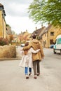 Rear view of a silhouette of a loving couple, hugging while visiting a destination city, walking along the old street of English