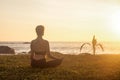 Rear view silhouette slim woman does yoga on tropical sea coast or ocean beach outdoors on sunset Royalty Free Stock Photo
