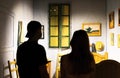 Rear view of a silhouette of two people looking at Van Goghs childhood room at an art exhibit