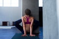 Rear view of sinewy girl doing stretching exercise for hamstrings, hip flexors and core muscles with wall in yoga center Royalty Free Stock Photo