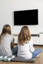 Rear view of sisters watching TV at home Royalty Free Stock Photo