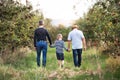 A small boy with father and grandfather walking in apple orchard in autumn. Royalty Free Stock Photo