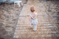 A rear view of small toddler girl walking on beach on summer holiday. Royalty Free Stock Photo