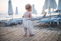 A rear view of small toddler girl walking on beach on summer holiday.