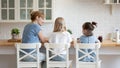 Rear view smiling mother with daughters sitting at kitchen table Royalty Free Stock Photo