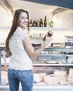 Rear view of smiling woman holding chocolate jar in front of display cabinet at cafe