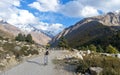 Rear View of Solo Indian traveler in winter clothing walking alone hiking a remote mountain road. Snow capped Himalayan mountain