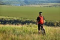 Rear view of the sportsman with his mountain bike stands on the meadow and looking away in the countryside. Royalty Free Stock Photo
