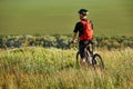 Rear view of the sportsman with his mountain bike stands on the meadow and looking away in the countryside. Royalty Free Stock Photo
