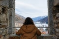 Rear view of standing tourist girl watching snowy mountains from the big window Royalty Free Stock Photo