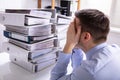 Stressed Businessman In Front Of Stacked Folders Royalty Free Stock Photo