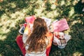 Rear view of a student female in casual outfit sitting on the green grass at the college campus, and studying with lots of books Royalty Free Stock Photo