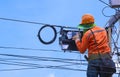 Technician on wooden ladder checking code numbers of fiber optic cable lines in internet splitter box for repairing on power pole Royalty Free Stock Photo