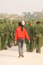 Rear view, Teen girl in red shirt walking with a group of Young Vietnamese soldier on the street, during site visit program. Dien