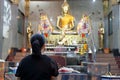 Rear view of Thai woman praying to Buddha in the temple