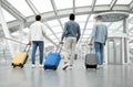 Rear View Of Three Tourists Men With Luggage In Airport