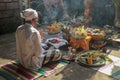 Rear view to Hindu priest praying during a wedding ceremony. Pedanda sits on the ground in front of the offerings and performs