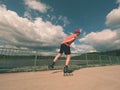 Rear view to inline skater in red t-shirt and black pants skating on the bridge . Outdoor inline skating