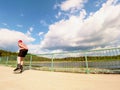 Rear view to inline skater in red t-shirt and black pants skating on the bridge . Outdoor inline skating