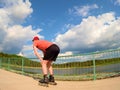 Rear view to inline skater in red t-shirt and black pants skating on the bridge . Outdoor inline skating