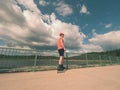 Rear view to inline skater in red t-shirt and black pants skating on the bridge . Outdoor inline skating