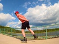 Rear view to inline skater in red t-shirt and black pants skating on the bridge . Outdoor inline skating