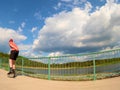 Rear view to inline skater in red t-shirt and black pants skating on the bridge . Outdoor inline skating