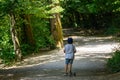 Rear view of toddler riding a three wheel scooter on gravel path in park Royalty Free Stock Photo