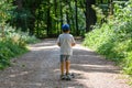 Rear view of toddler riding a three wheel scooter on gravel path in park Royalty Free Stock Photo