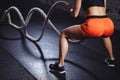 Rear view of tonned woman training with battle rope in cross fit gym Royalty Free Stock Photo