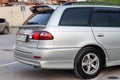 Rear view of Toyota Caldina car of 2000 release in the back of a silver T210 station wagon with two spoilers on trunk in a parking