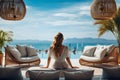 Rear view of traveler woman relaxing lounging on couch in luxury hotel. Female enjoying on outdoor patio sofa. Summer, holiday Royalty Free Stock Photo