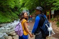 A young couple crossing a mountain stream while out walking together. Travelers stand near waterfalls.