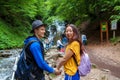 A young couple crossing a mountain stream while out walking together. Travelers stand near waterfalls.