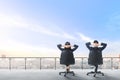 Rear view of two asian business people sitting on the office chair in modern terrace relax and looking at view on the city