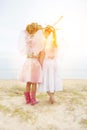 Rear view of two little girls dressed as angels with strong lens flare Royalty Free Stock Photo